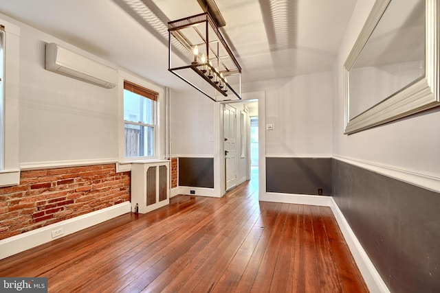 interior space with radiator heating unit, hardwood / wood-style floors, a wall mounted AC, and brick wall