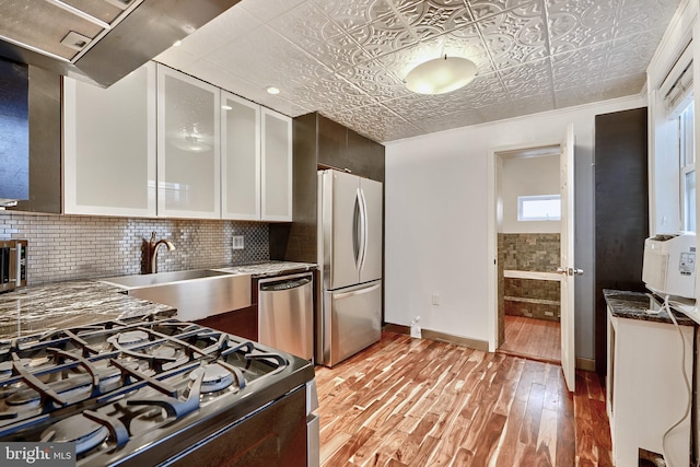 kitchen featuring light hardwood / wood-style floors, appliances with stainless steel finishes, tasteful backsplash, crown molding, and white cabinets