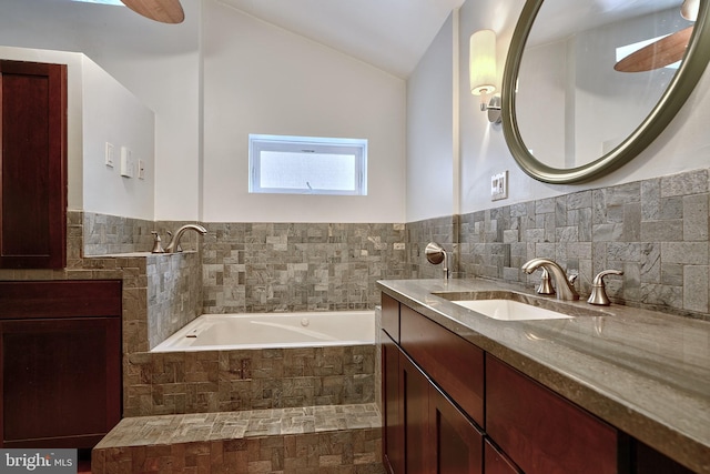 bathroom featuring tiled bath, vanity, and lofted ceiling