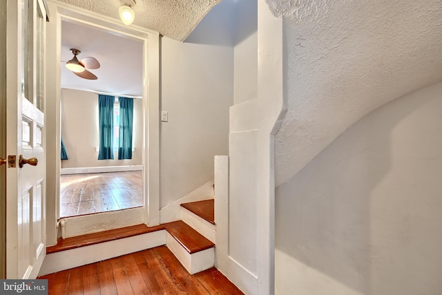 staircase with hardwood / wood-style floors and a textured ceiling