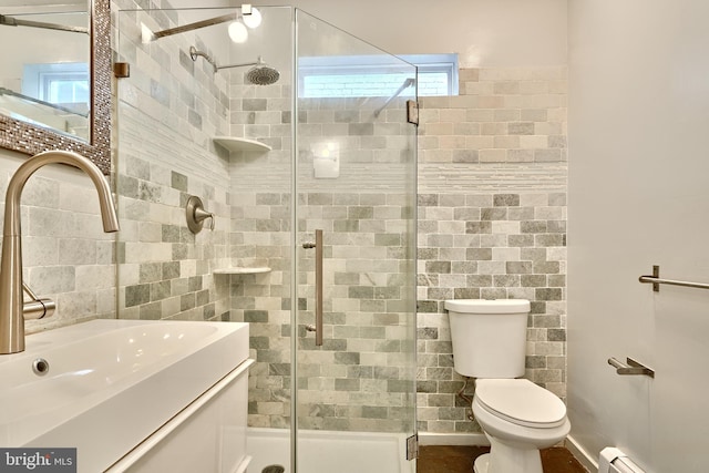 bathroom with toilet, vanity, an enclosed shower, and baseboard heating