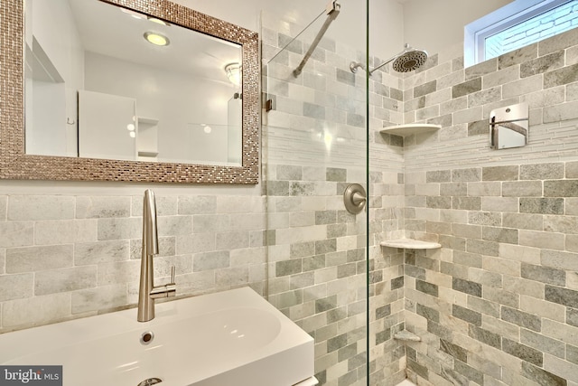 bathroom with sink, a tile shower, and backsplash