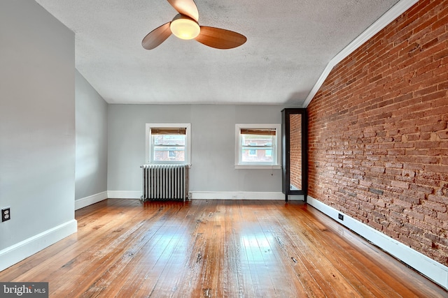 spare room featuring a textured ceiling, radiator heating unit, and light hardwood / wood-style flooring