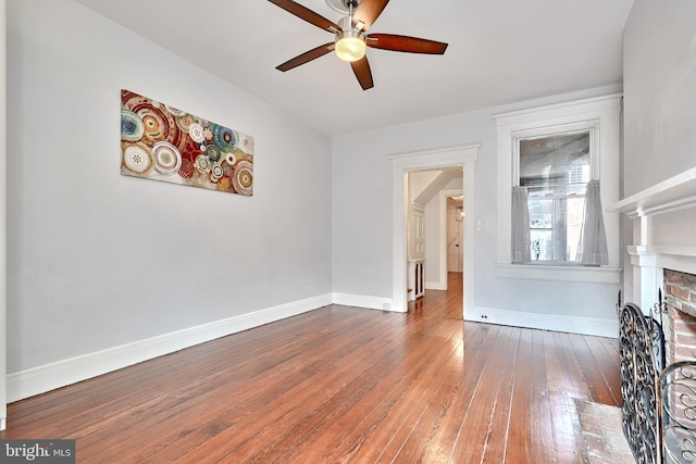 unfurnished living room with dark wood-type flooring, ceiling fan, and a fireplace