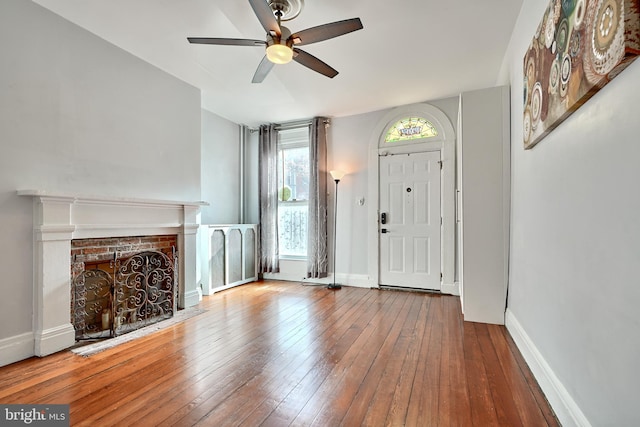 entrance foyer with a fireplace, hardwood / wood-style flooring, ceiling fan, and radiator heating unit