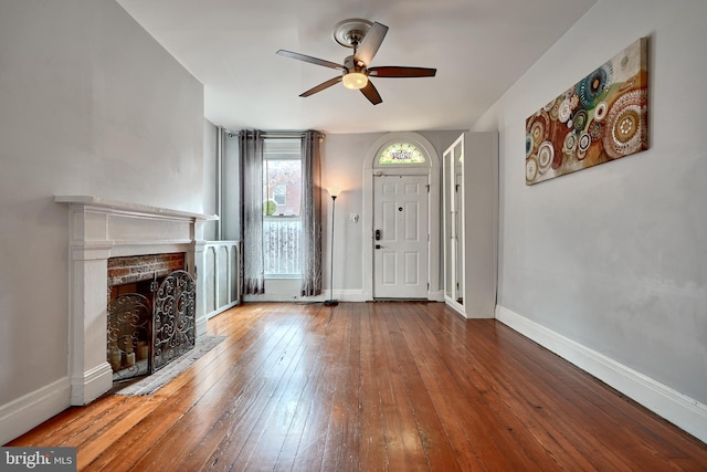 foyer entrance featuring ceiling fan, wood-type flooring, and a fireplace