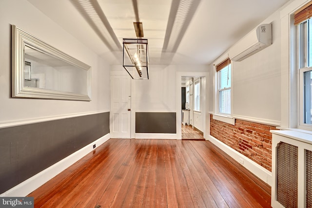 spare room featuring an AC wall unit, hardwood / wood-style floors, and brick wall