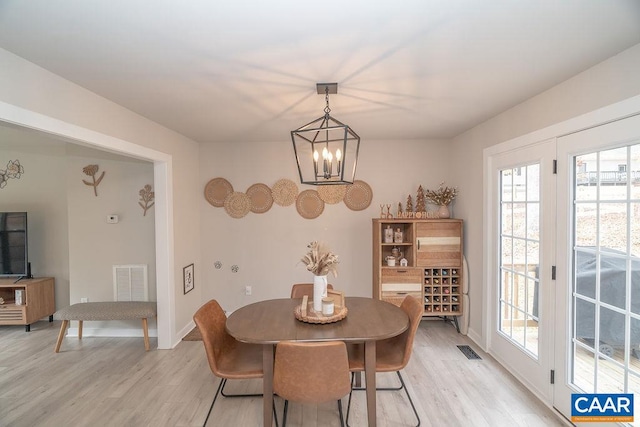 dining area featuring light wood-type flooring and a notable chandelier