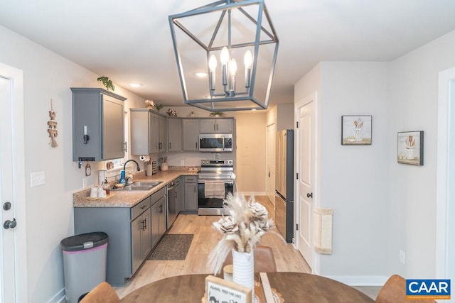 kitchen featuring sink, appliances with stainless steel finishes, hanging light fixtures, light hardwood / wood-style flooring, and gray cabinets