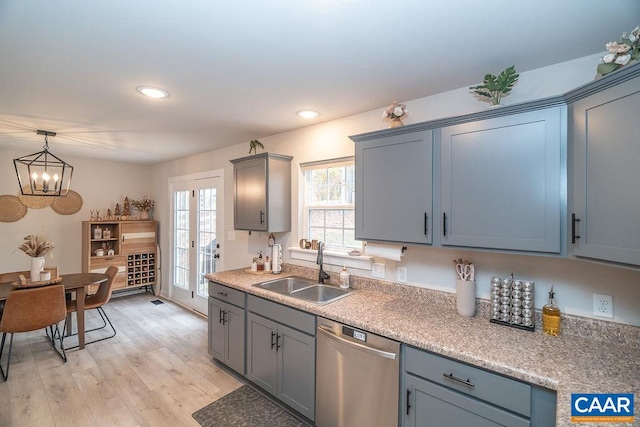 kitchen featuring a notable chandelier, hanging light fixtures, sink, light hardwood / wood-style floors, and dishwasher