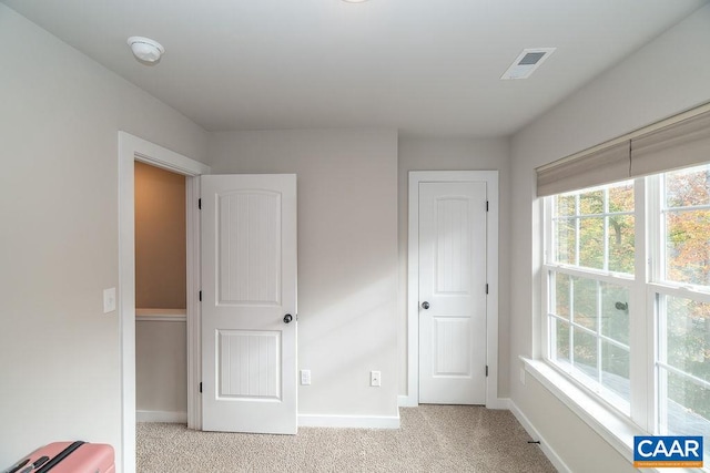 unfurnished bedroom featuring multiple windows and light carpet