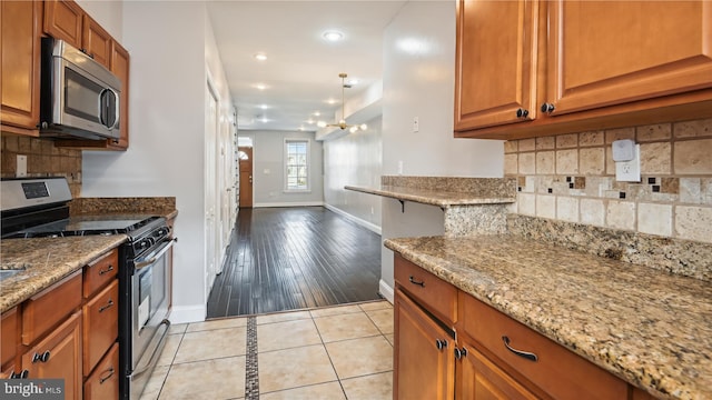 kitchen with light stone countertops, light wood-type flooring, and appliances with stainless steel finishes