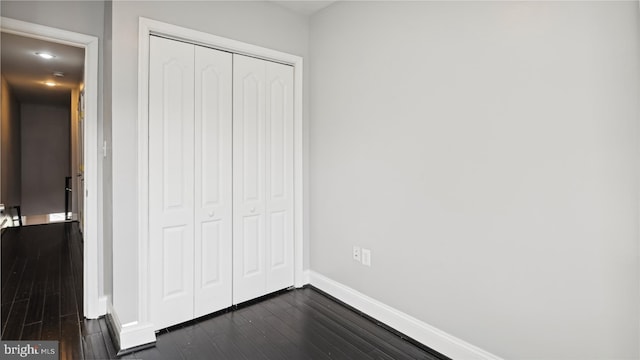 unfurnished bedroom with dark hardwood / wood-style flooring and a closet