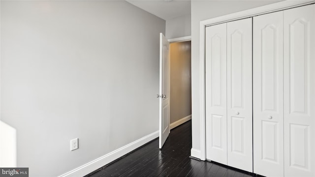 unfurnished bedroom featuring a closet and dark hardwood / wood-style flooring