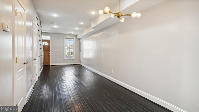 spare room featuring dark hardwood / wood-style floors and a chandelier