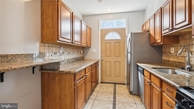 kitchen with light tile patterned floors, sink, backsplash, and stone countertops