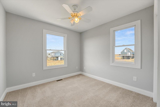 carpeted spare room featuring ceiling fan and a healthy amount of sunlight