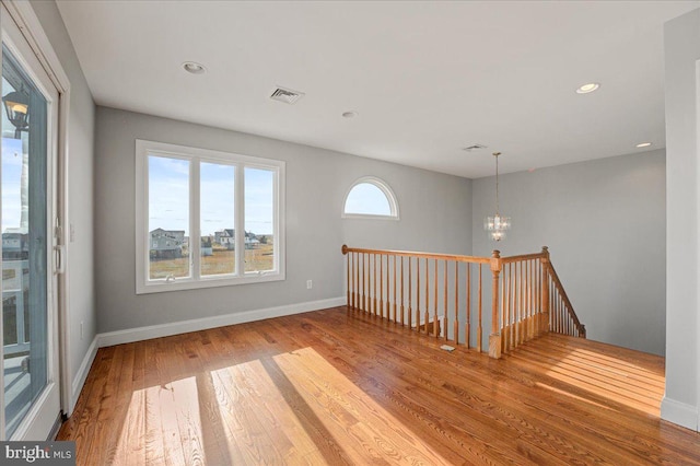 unfurnished room with a chandelier and hardwood / wood-style floors