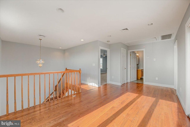 unfurnished room with light wood-type flooring and a chandelier