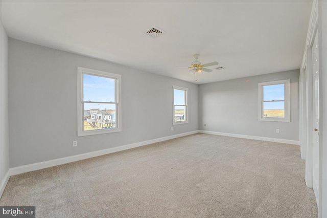 carpeted spare room featuring ceiling fan and a healthy amount of sunlight