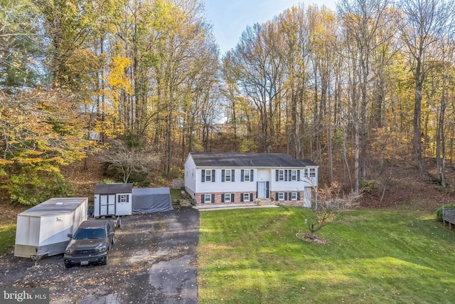 split foyer home with a front yard and a storage unit