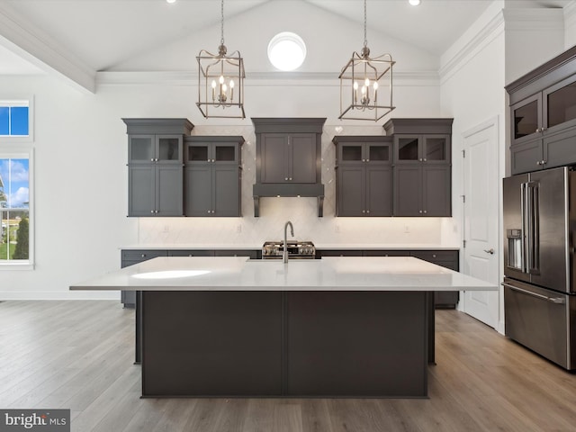 kitchen featuring a center island with sink, high end fridge, dark brown cabinetry, and light hardwood / wood-style flooring