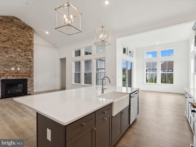 kitchen with light wood-type flooring, decorative light fixtures, lofted ceiling, and sink