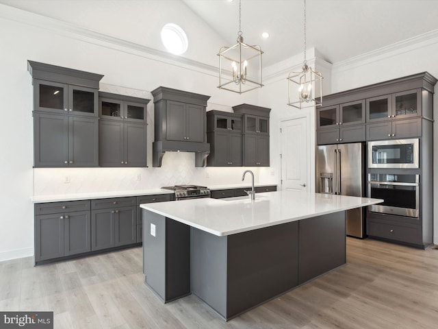 kitchen with sink, light hardwood / wood-style flooring, pendant lighting, a center island with sink, and appliances with stainless steel finishes