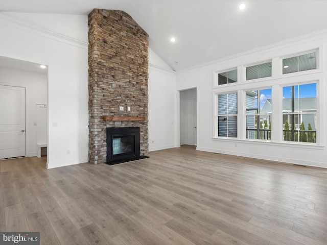 unfurnished living room featuring crown molding, a fireplace, high vaulted ceiling, and light hardwood / wood-style floors