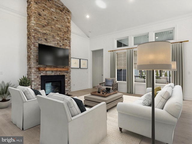 living room featuring crown molding, light hardwood / wood-style flooring, lofted ceiling, and a stone fireplace