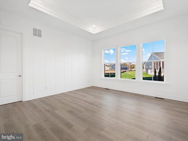 unfurnished room with light hardwood / wood-style floors, ornamental molding, and a tray ceiling