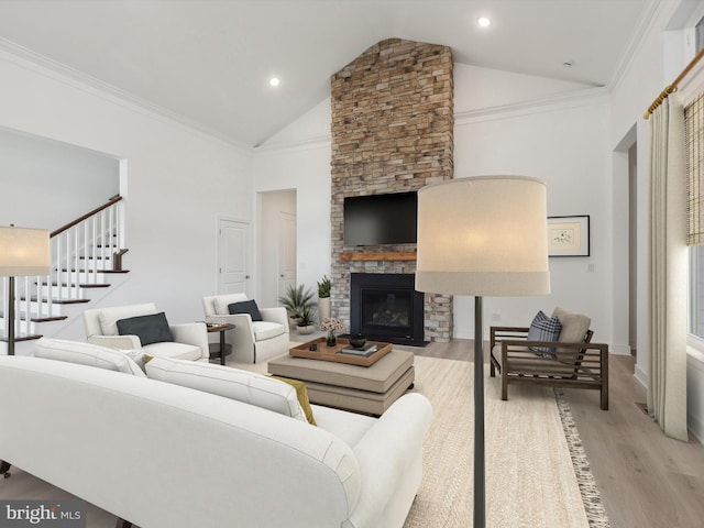 living room with a fireplace, crown molding, light hardwood / wood-style flooring, and vaulted ceiling