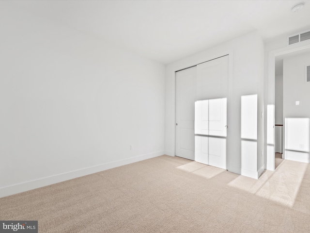 unfurnished bedroom with light colored carpet and a closet