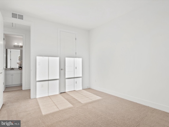 unfurnished bedroom with light colored carpet and connected bathroom