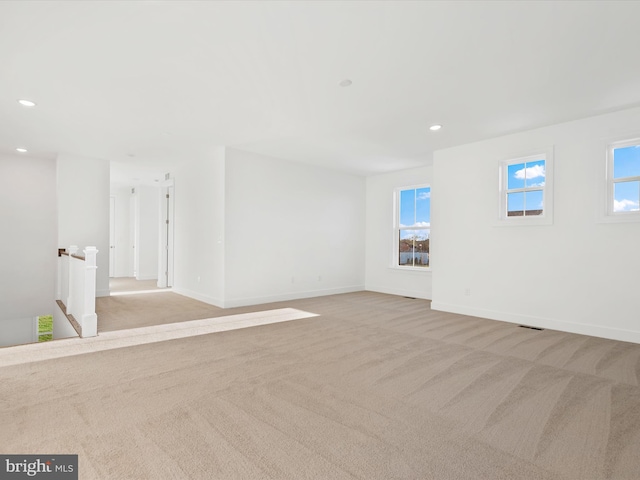 unfurnished room featuring light carpet and a wealth of natural light