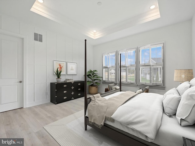 bedroom featuring light wood-type flooring and a tray ceiling