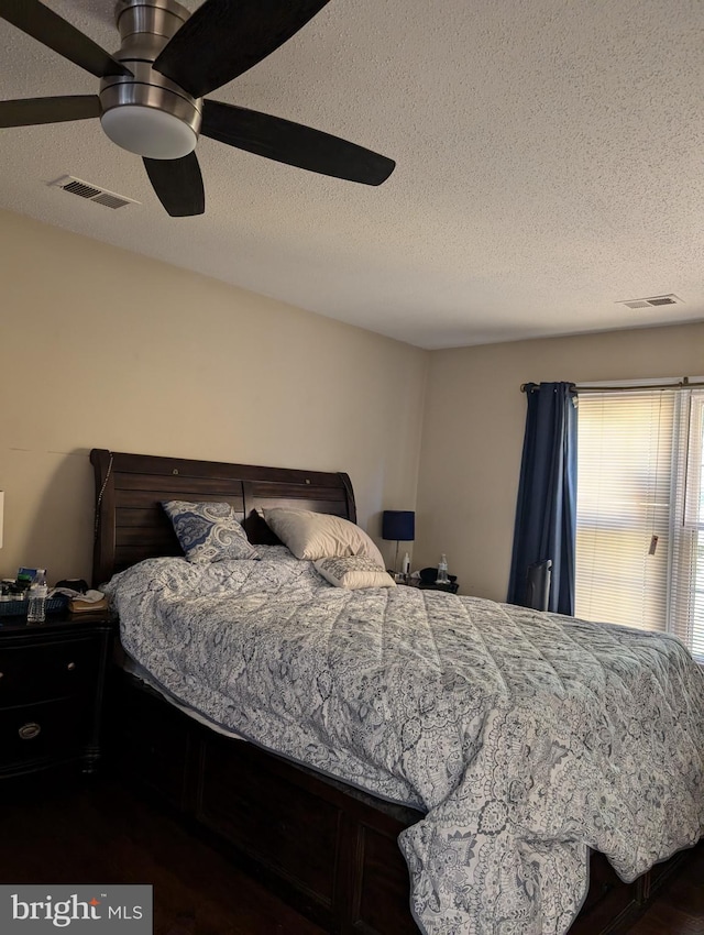 bedroom with dark hardwood / wood-style floors, ceiling fan, and a textured ceiling