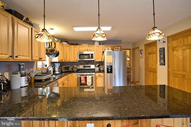 kitchen with dark stone countertops, pendant lighting, appliances with stainless steel finishes, and sink