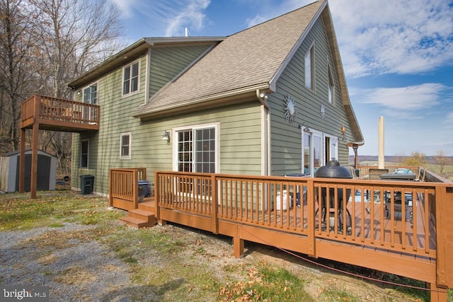 rear view of property featuring a shed and a deck