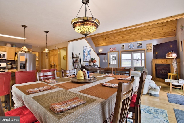 dining area featuring light wood-type flooring and vaulted ceiling