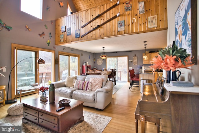 living room featuring a healthy amount of sunlight, light wood-type flooring, high vaulted ceiling, and wood ceiling