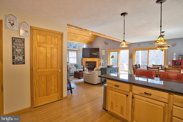 kitchen featuring hanging light fixtures, dark stone counters, light hardwood / wood-style flooring, and lofted ceiling