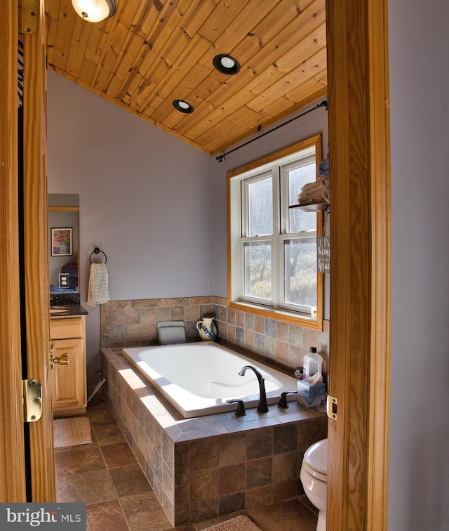 bathroom featuring wooden ceiling, tiled bath, vanity, and toilet