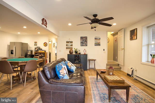 living room featuring light wood-type flooring, baseboard heating, and ceiling fan