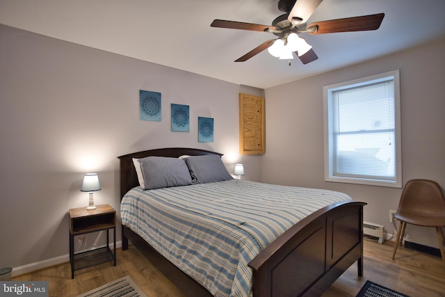 bedroom with a baseboard heating unit, hardwood / wood-style floors, and ceiling fan