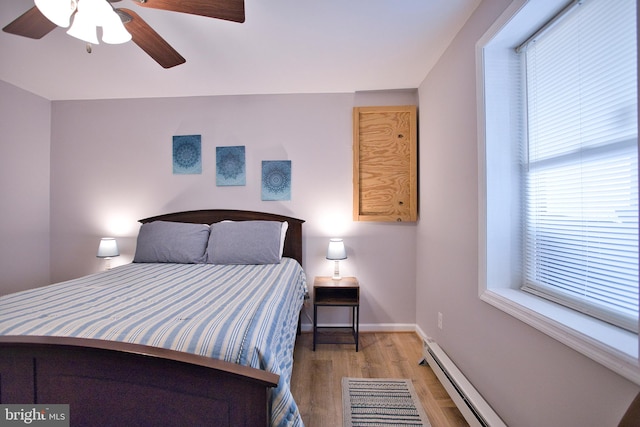 bedroom with ceiling fan, light wood-type flooring, and baseboard heating