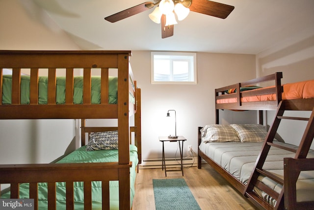 bedroom featuring ceiling fan, light hardwood / wood-style floors, and a baseboard heating unit