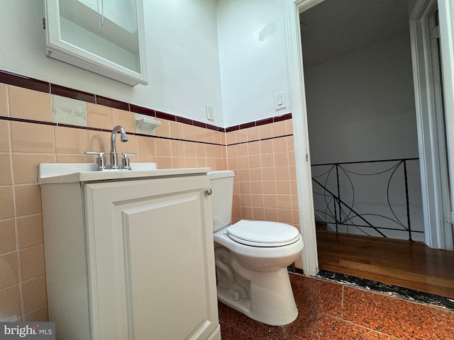 bathroom with tile walls, vanity, and toilet