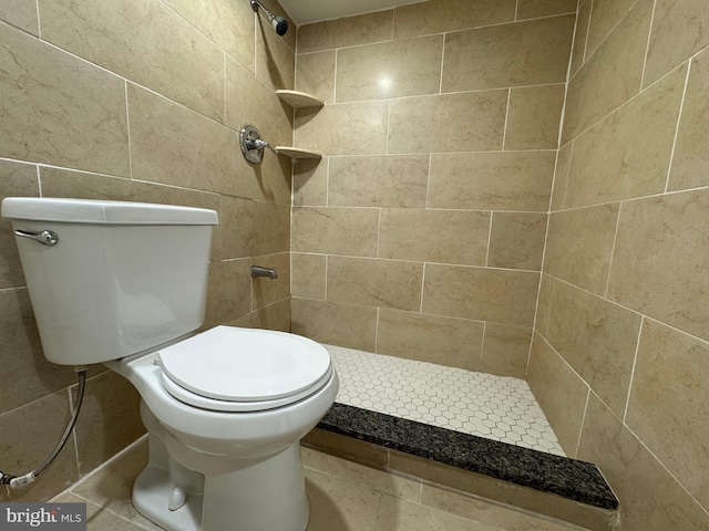 bathroom with toilet, tile walls, and tiled shower