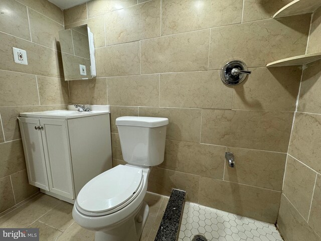 bathroom featuring walk in shower, vanity, and tile walls